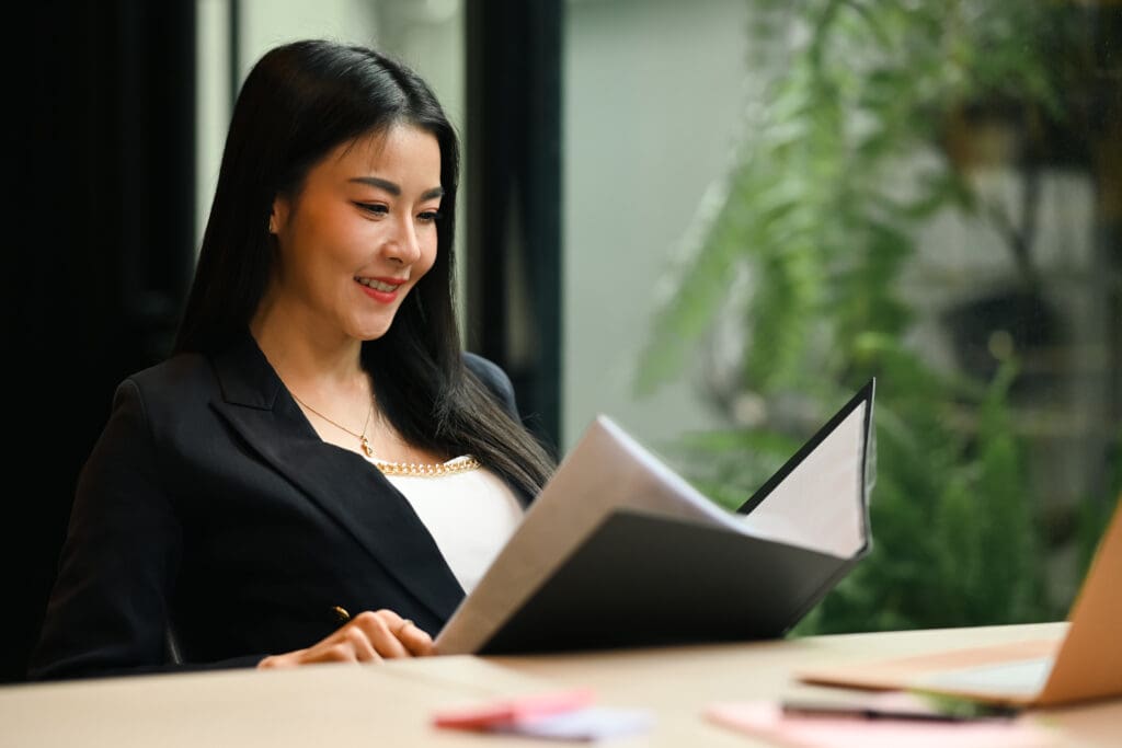 Smiling female manager checking financial report or correspondence at her workplace.