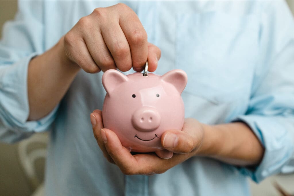 Woman putting coin in pink piggy bank for business. Saving money or savings, investment concept
